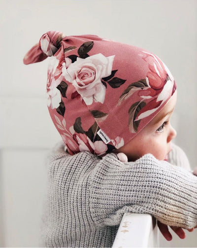 Toddler wearing pink floral top knot beanie