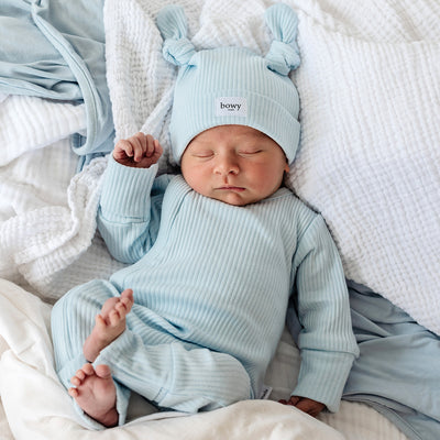 Baby resting on white linen wearing a matching powder blue ribbed cotton set