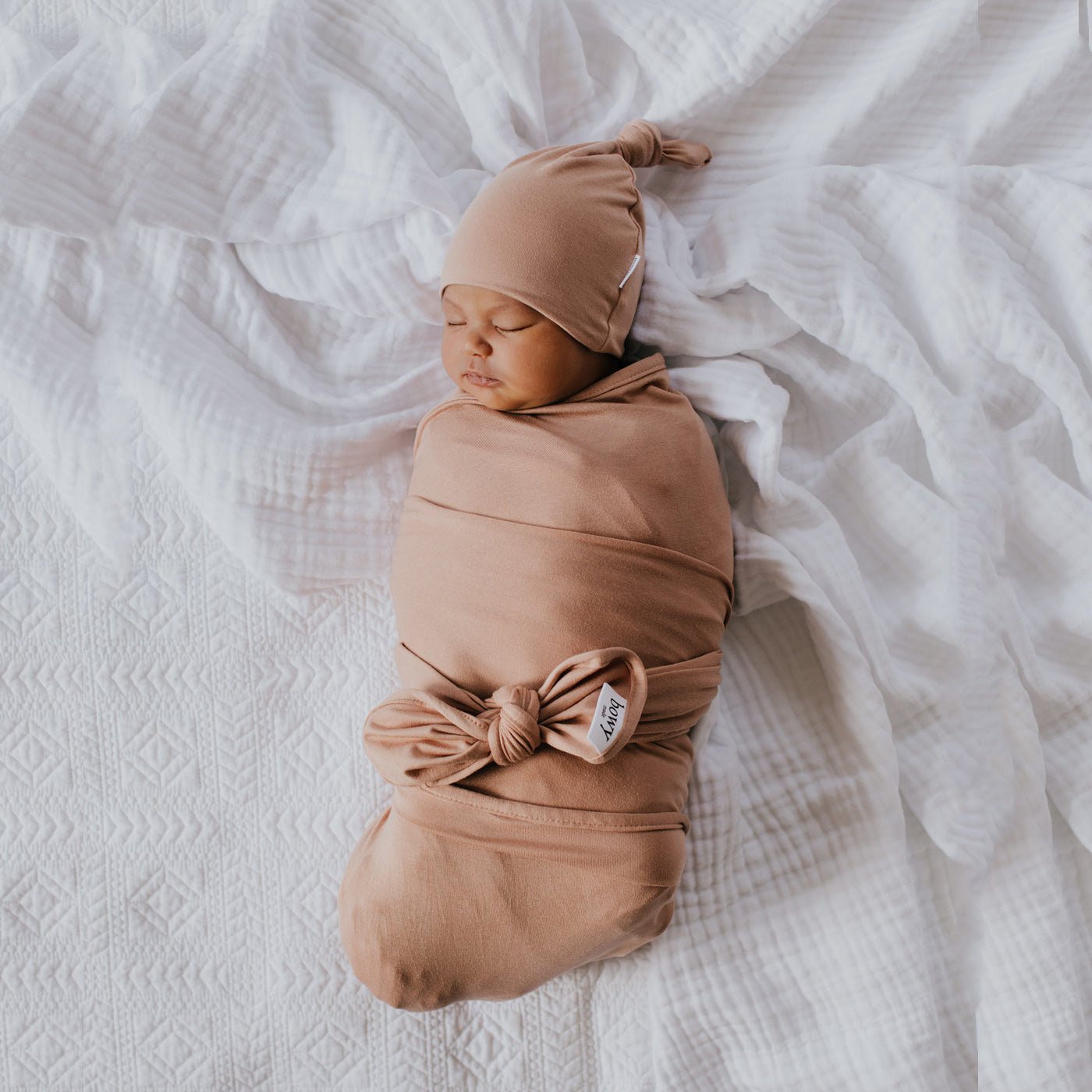 baby wrapped in tan colour swaddle