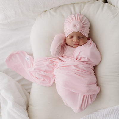 cute baby wearing pink turban wrapped in pink swaddle