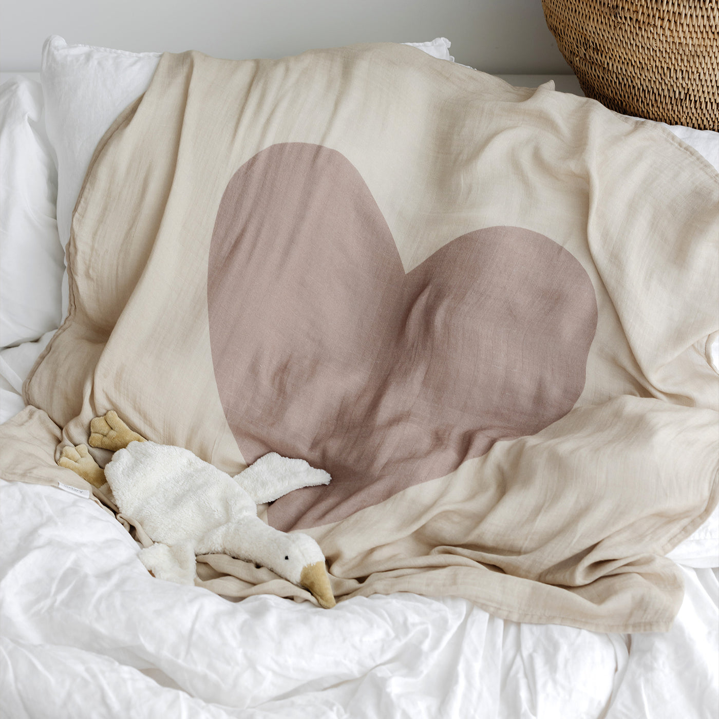 Heart-shaped pillow on a bed with a soft blanket and toy