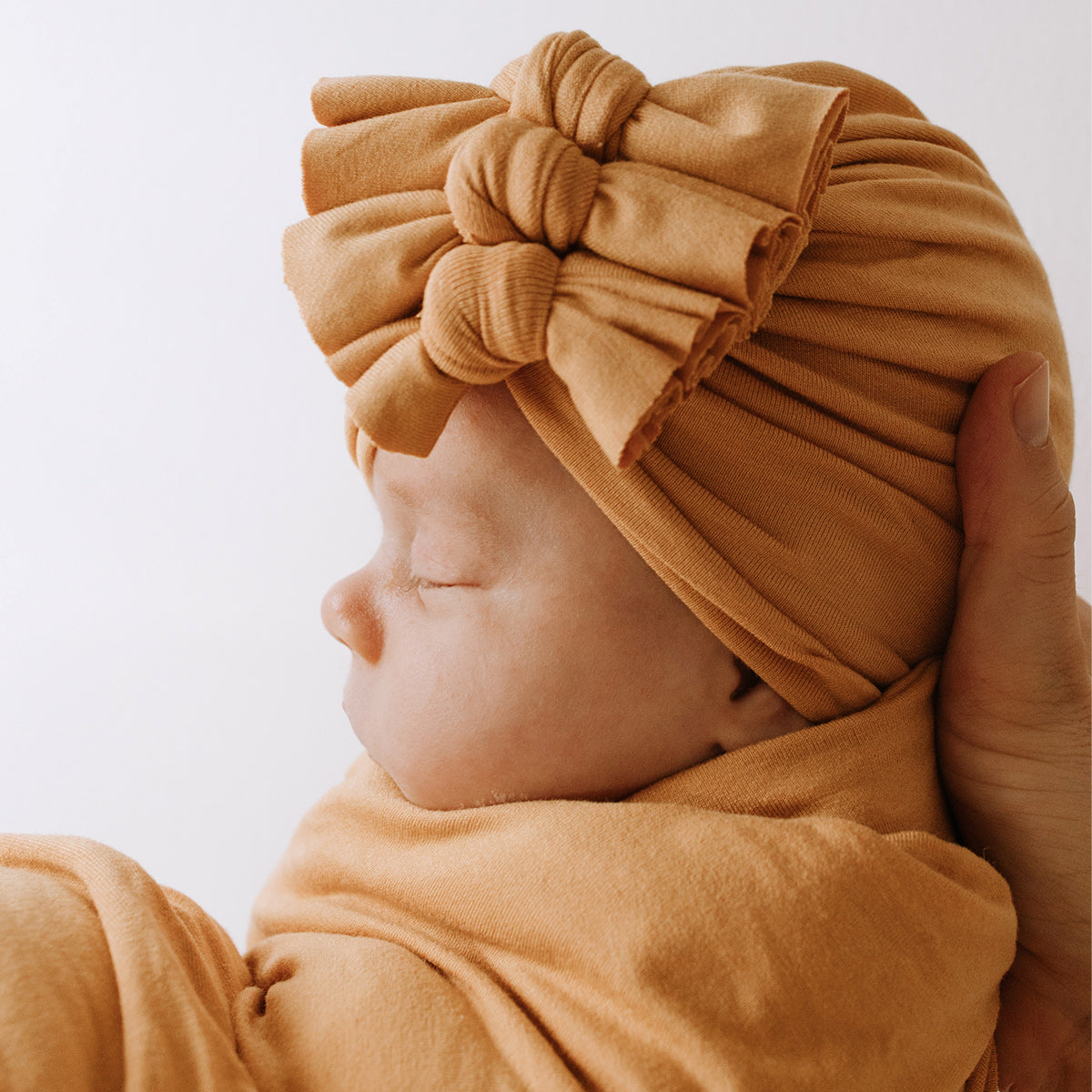 Baby being held wearing 3 bow baby beanie