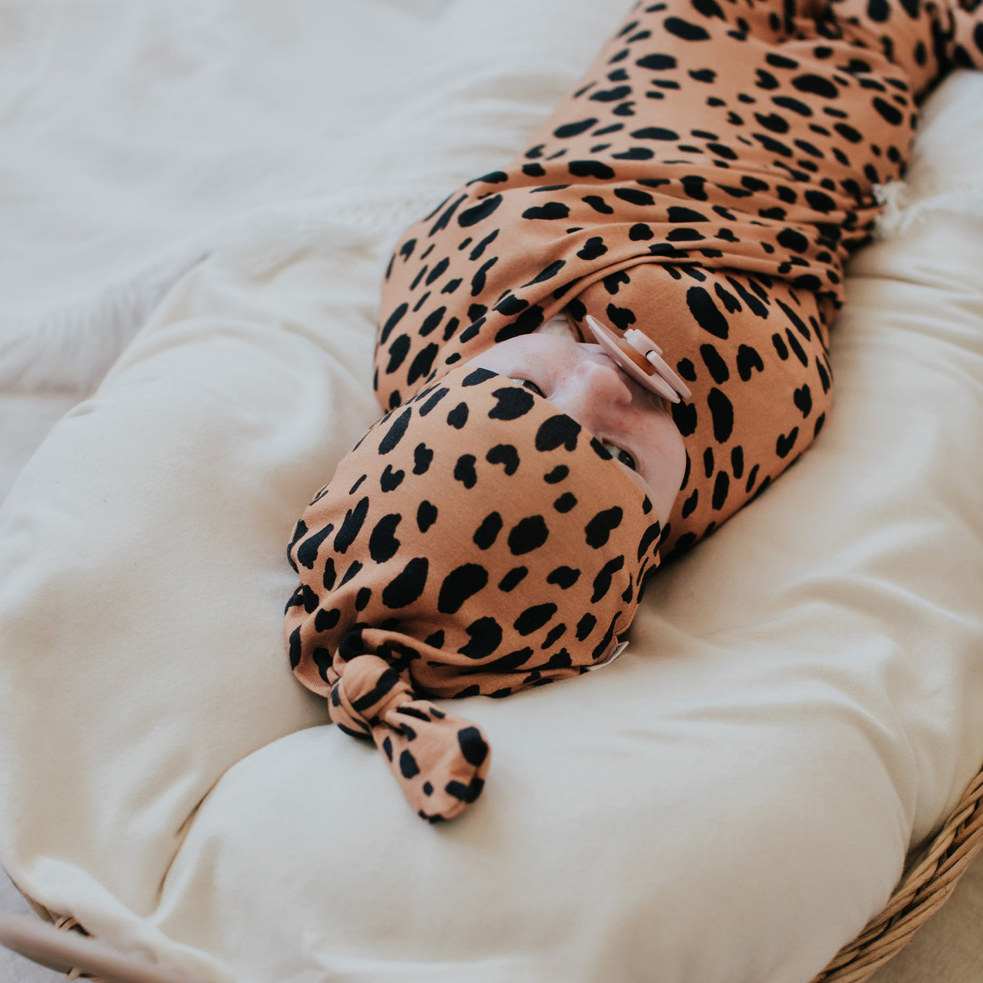 Newborn baby wearing top knot beanie in cheetah print