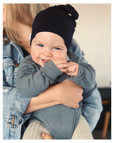 Baby boy smiling wearing navy colour top knot beanie 