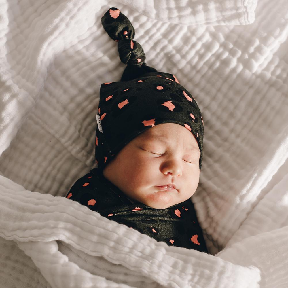 Cute baby sleeping wearing green and pink top knot beanie