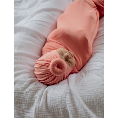 Sleeping baby wearing bright color swaddle and matching headwear